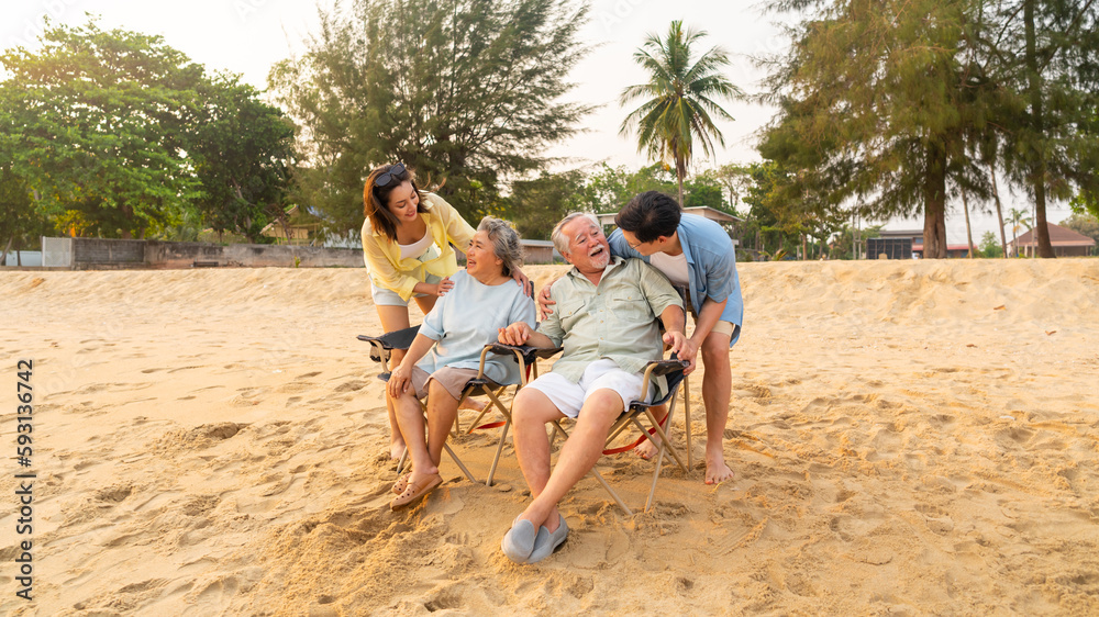 Fototapeta premium Happy Asian family travel ocean on summer holiday vacation. Adult couple and aging parents enjoy and fun outdoor activity lifestyle resting and talking together at tropical island beach at sunset.