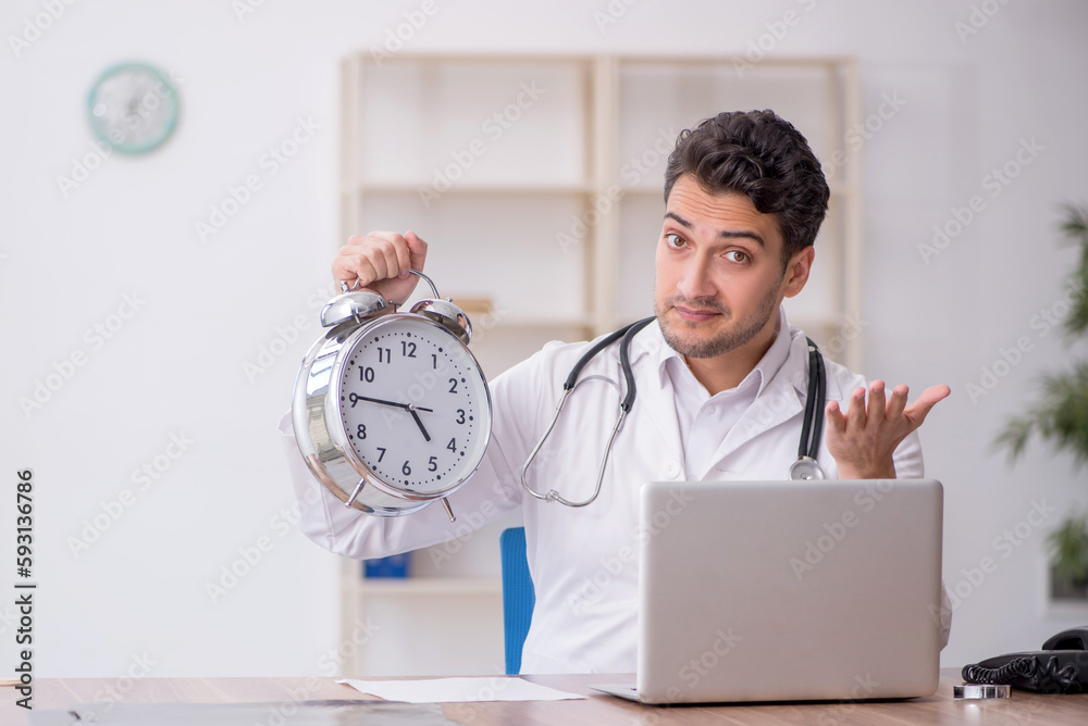 Young male doctor in time management concept Young male doctor in time management concept