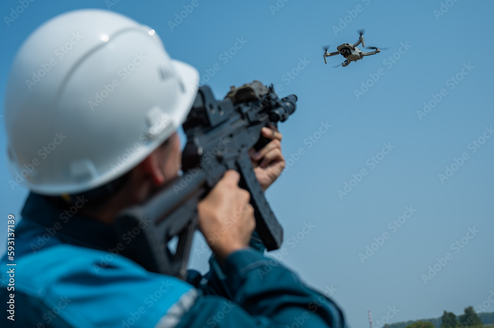 Caucasian man in a helmet shoots a flying drone with a rifle. Caucasian man in a helmet shoots a flying drone with a rifle.