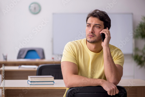 Young male student teacher sitting in the classroom