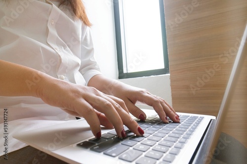 Business woman typing on laptop selected focus on right hand in business technology concept.