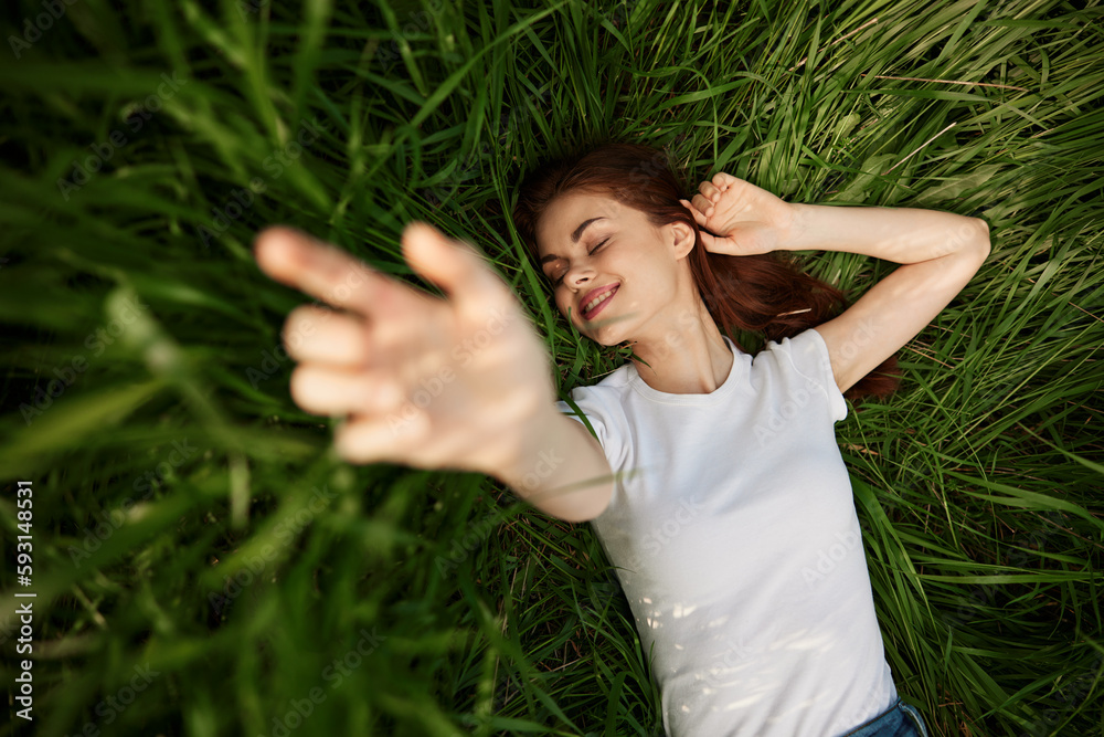 laughing redhead woman stretching her palms to the camera while lying on the grass laughing redhead woman stretching her palms to the camera while lying on the grass