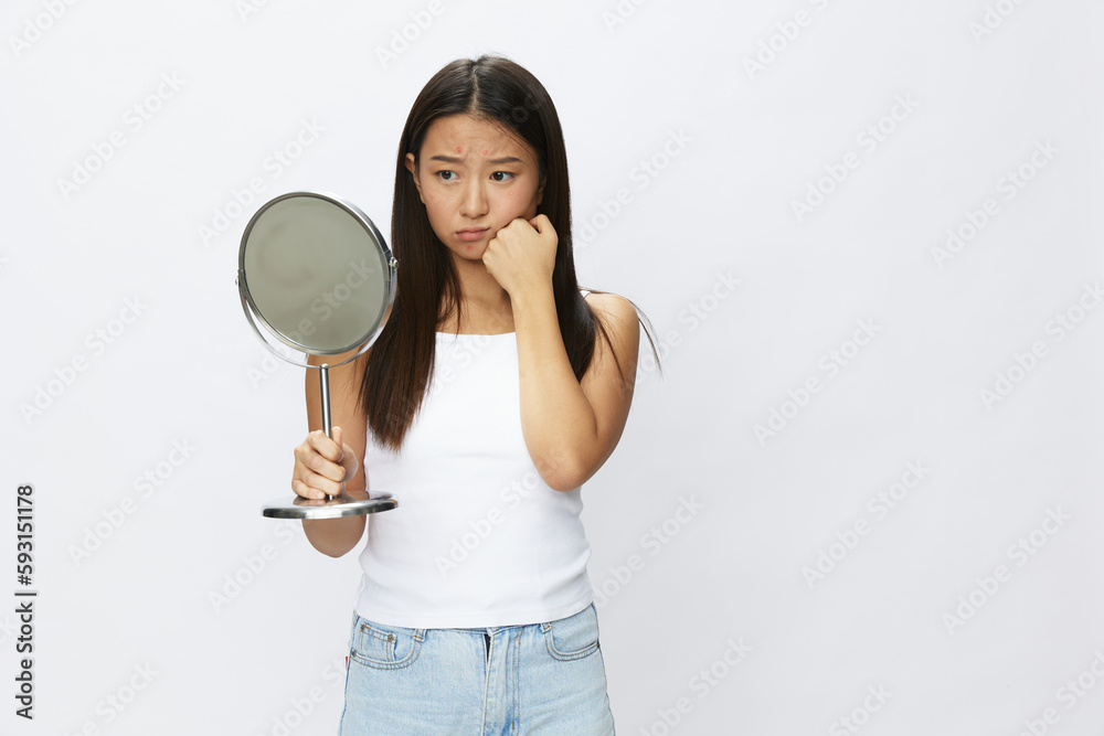 Asian woman with mirror in hand facial skin problems, acne and inflammation, red rash and allergies, chicken pox, sadness from rashes. Facial skin care concept for diseases and nerves Asian woman with mirror in hand facial skin problems, acne and inflammation, red rash and allergies, chicken pox, sadness from rashes. Facial skin care concept for diseases and nerves