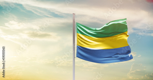 Gabon national flag waving in beautiful sky. The symbol of the state on wavy silk fabric.