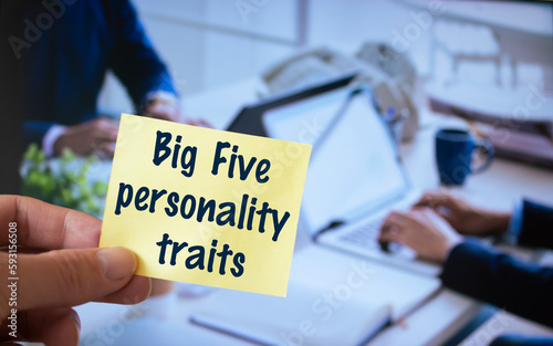 Male hand holding sticky note written Big Five personality traits.