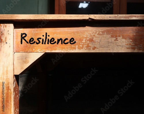 Desk with word inscription RESILIENCE, means capacity to recover quickly from difficulties and toughness - ability to cope crisis and spring back to normal quickly