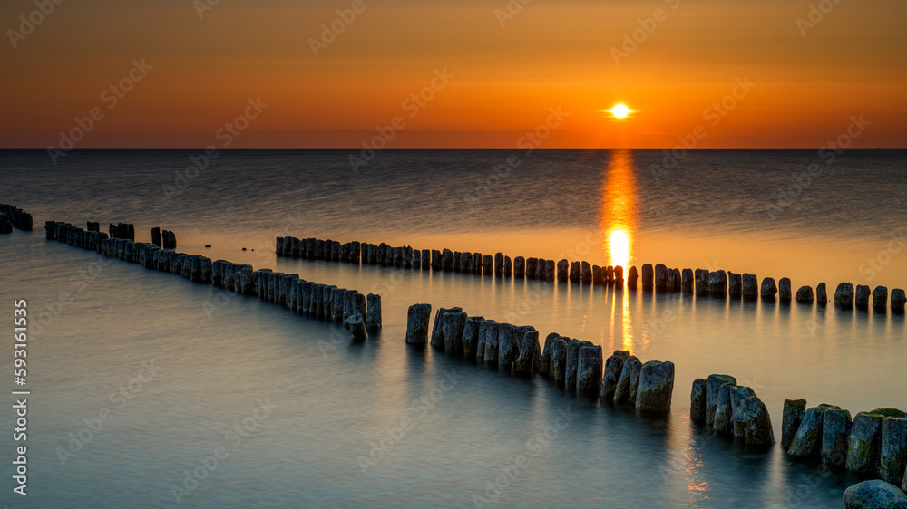 Obraz premium Sonnenuntergang in Dranske auf der Insel Rügen, im Vordergrund Buhnen