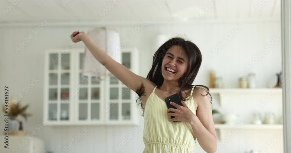 Excited happy gen Z smartphone user girl typing on gadget at home, looking at screen in surprise, joy, shouting wow, jumping to feet, celebrating success, win, good news Excited happy gen Z smartphone user girl typing on gadget at home, looking at screen in surprise, joy, shouting wow, jumping to feet, celebrating success, win, good news