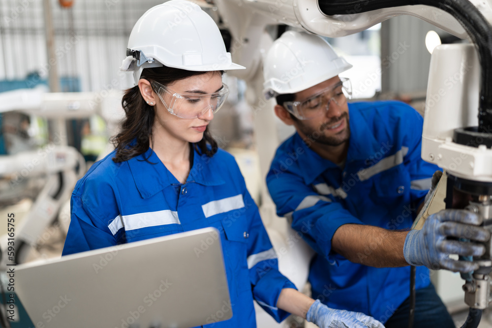 Man and woman engineer checking arm robot with remote control Man and woman engineer checking arm robot with remote control