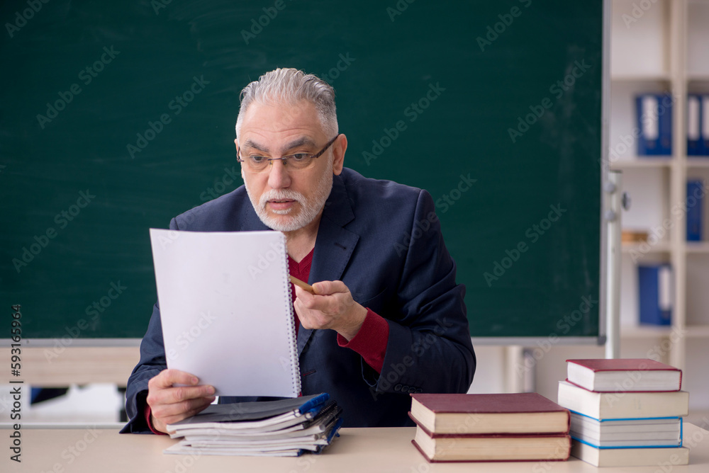 Old male teacher sitting in the classroom Old male teacher sitting in the classroom