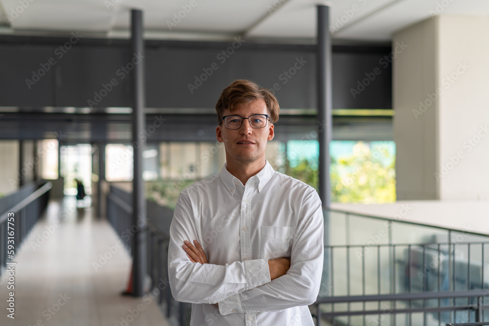 Smiling businessman with arms crossed on blurred office hall background Smiling businessman with arms crossed on blurred office hall background