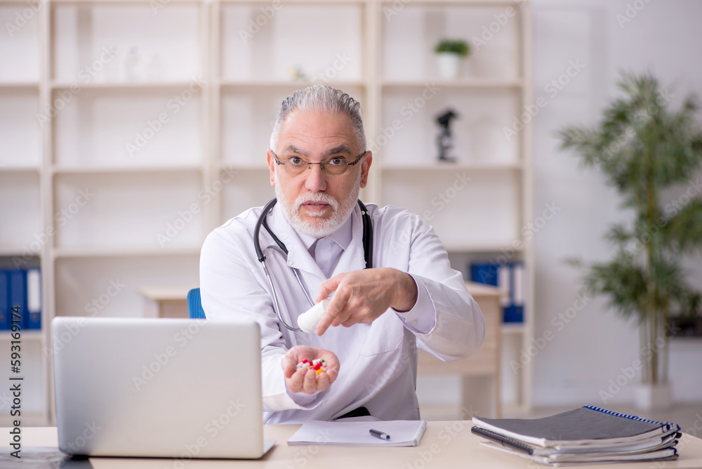 Old male doctor suggesting pills in the clinic Old male doctor suggesting pills in the clinic
