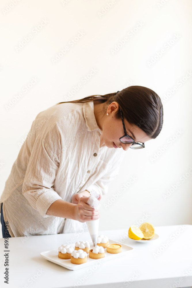 female confectioner is putting cream on lemon sweets in her kitchen female confectioner is putting cream on lemon sweets in her kitchen