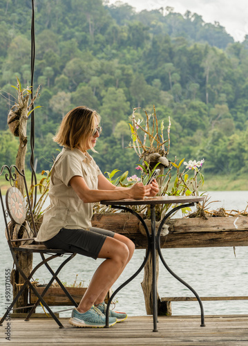 Woman sitting looking at her mobile phone in khao sok national park photo
