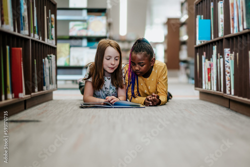 Young girls reading a library book together inside