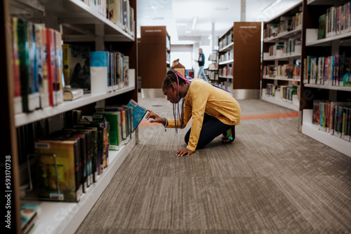 Young girl choosing book in library photo