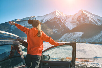 Happy Female in car enjoying winter mountain landscape, Woman traveling exploring, enjoying the view of the mountains. 
