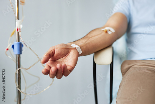 Minimal closeup of male arm with IV drip infusion in treatment session at clinic