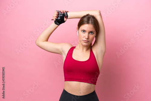 Young caucasian woman isolated on pink background stretching