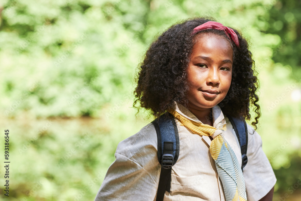 Waist up portrait of cute black girl as girl scout looking at camera outdoors in forest, copy space Waist up portrait of cute black girl as girl scout looking at camera outdoors in forest, copy space