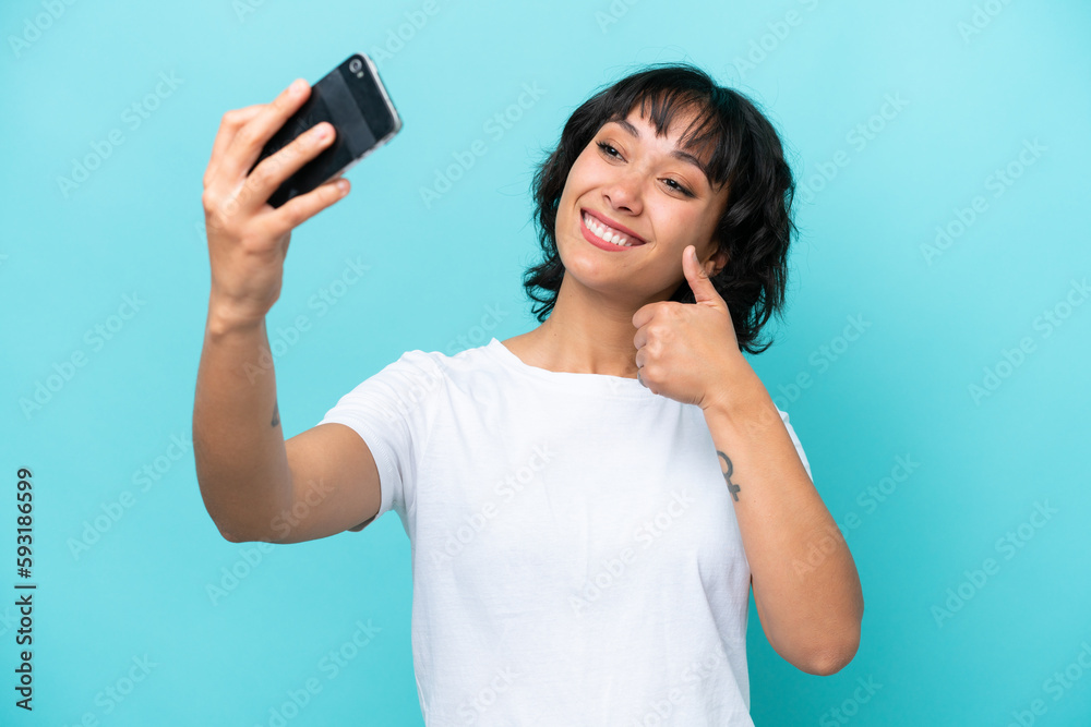 Young Argentinian woman isolated on blue background making a selfie with mobile phone Young Argentinian woman isolated on blue background making a selfie with mobile phone