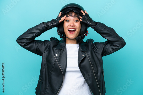 Young Argentinian woman with a motorcycle helmet isolated on blue background with surprise expression © luismolinero