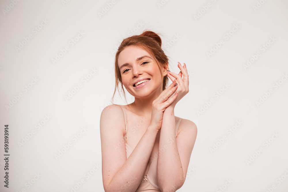 Beautiful young happy fresh redhead model girl with a cute smile and clean skin applies cream on her hands and does skin care on a white background. Beauty and health Beautiful young happy fresh redhead model girl with a cute smile and clean skin applies cream on her hands and does skin care on a white background. Beauty and health