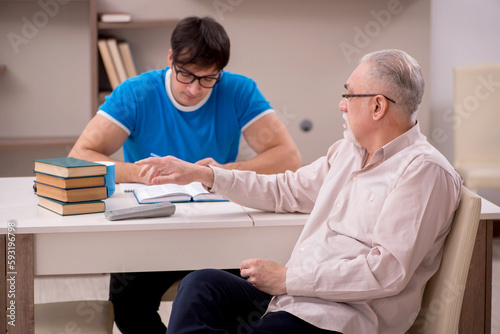 Young male student and his grandfather at home