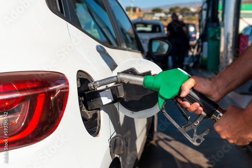 Man with the gun refueling gasoline or diesel fuel in a white car. Concept of transportation, energy crisis, oil crisis. Full tank in the midst of a price crisis at the gas pump