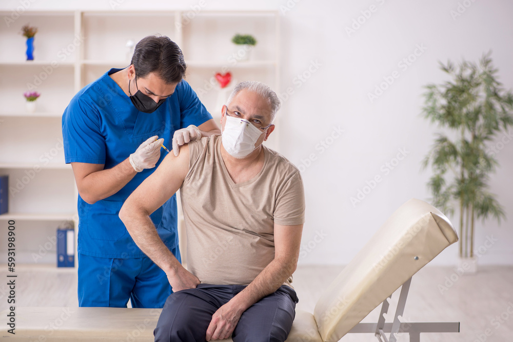 Fototapeta premium Old male patient visiting young male doctor in vaccination conce