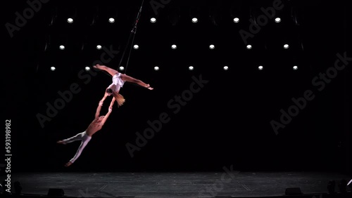 Aerial straps duo with white costume on black stage background performing at high altitude photo