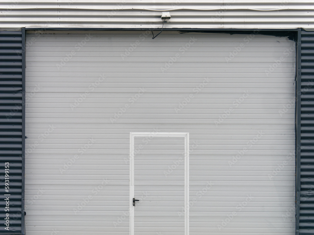 Minimalistic photo of the metal garage door at the modern building with security camera placed above them Minimalistic photo of the metal garage door at the modern building with security camera placed above them