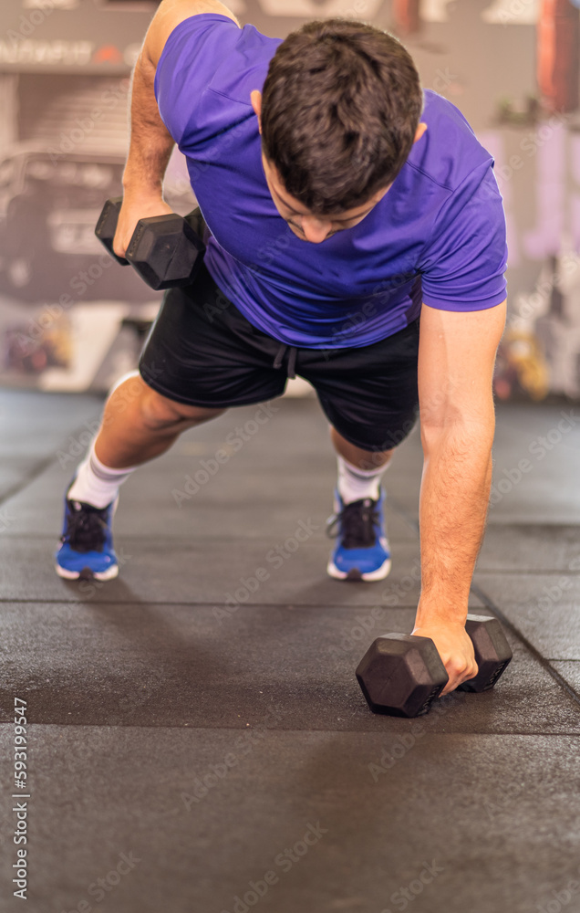 Young Man Training Hard In The Health Club. In The Gym Young Man Training Hard In The Health Club. In The Gym