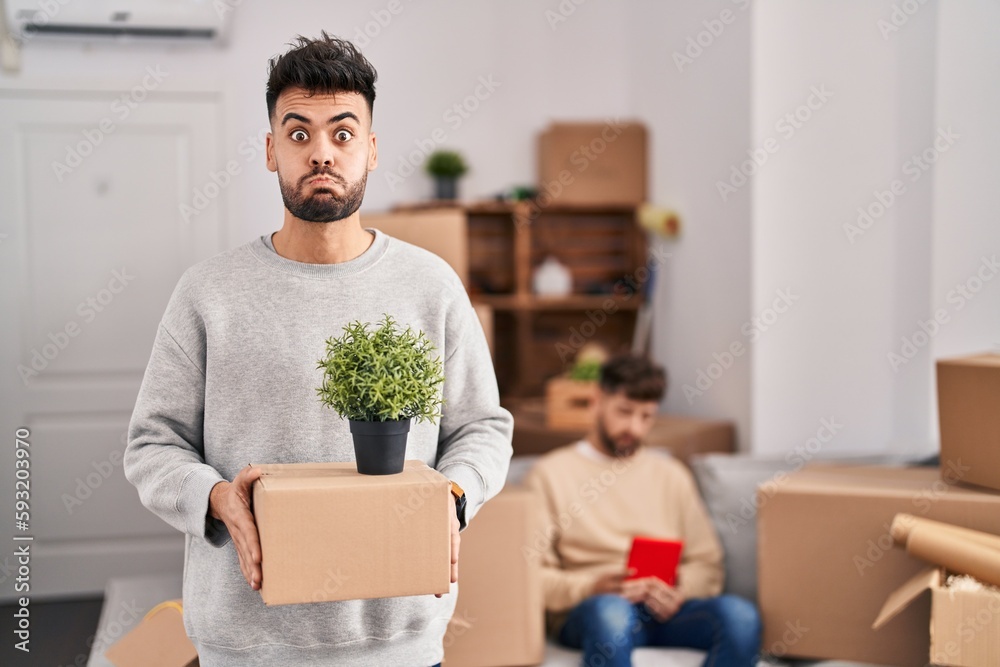 Homosexual couple moving to a new home puffing cheeks with funny face. mouth inflated with air, catching air. Homosexual couple moving to a new home puffing cheeks with funny face. mouth inflated with air, catching air.