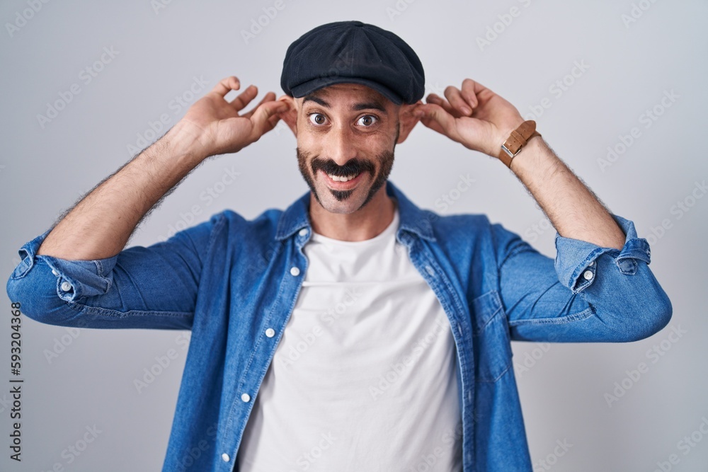 Hispanic man with beard standing over isolated background smiling pulling ears with fingers, funny gesture. audition problem Hispanic man with beard standing over isolated background smiling pulling ears with fingers, funny gesture. audition problem