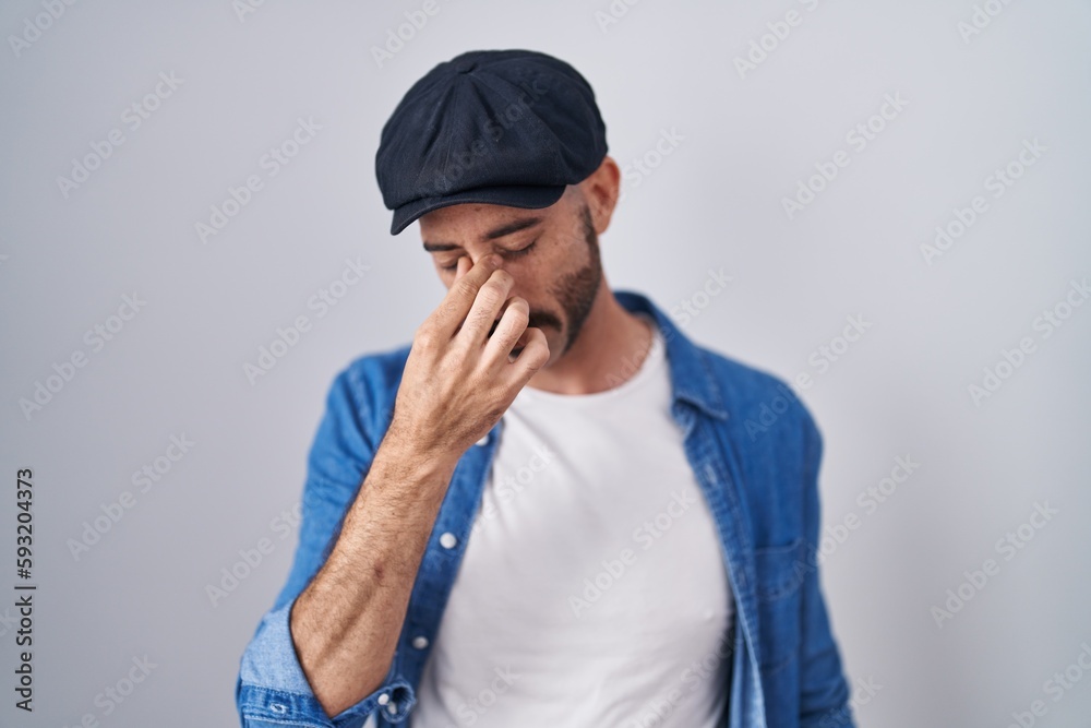 Hispanic man with beard standing over isolated background tired rubbing nose and eyes feeling fatigue and headache. stress and frustration concept. Hispanic man with beard standing over isolated background tired rubbing nose and eyes feeling fatigue and headache. stress and frustration concept.