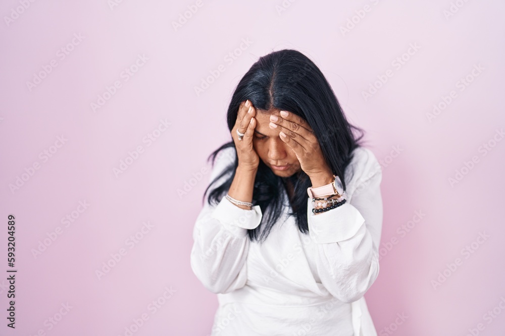 Mature hispanic woman standing over pink background with sad expression covering face with hands while crying. depression concept. Mature hispanic woman standing over pink background with sad expression covering face with hands while crying. depression concept.