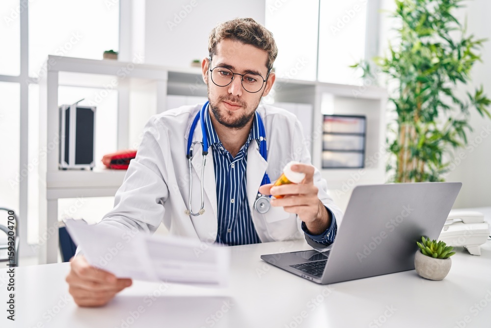 Young man doctor reading medical report holding pills at clinic Young man doctor reading medical report holding pills at clinic