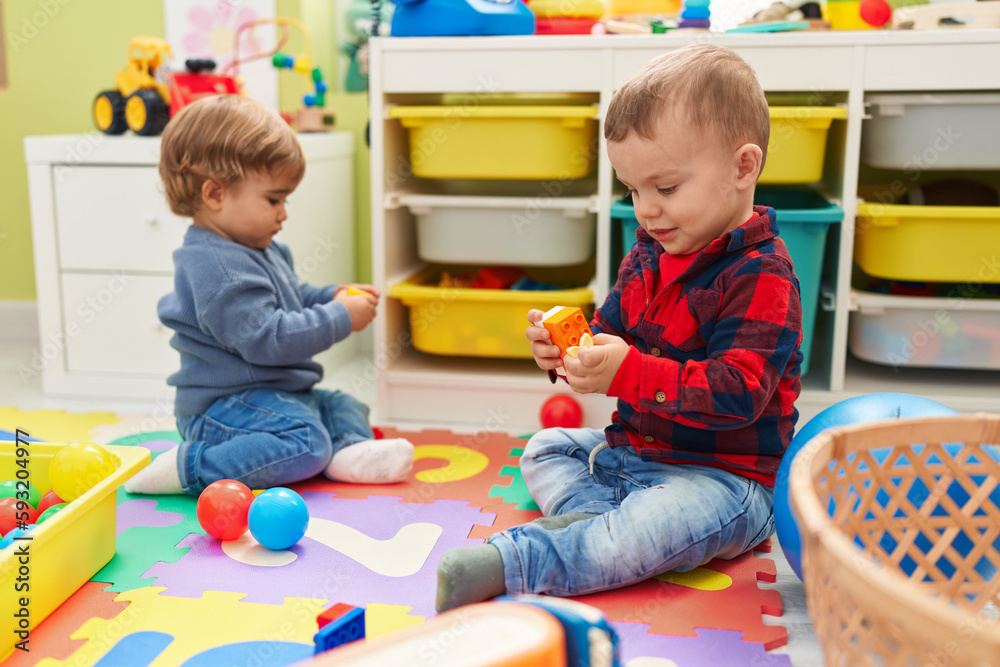 Adorable boys playing with balls and construction blocks sitting on floor at kindergarten Adorable boys playing with balls and construction blocks sitting on floor at kindergarten