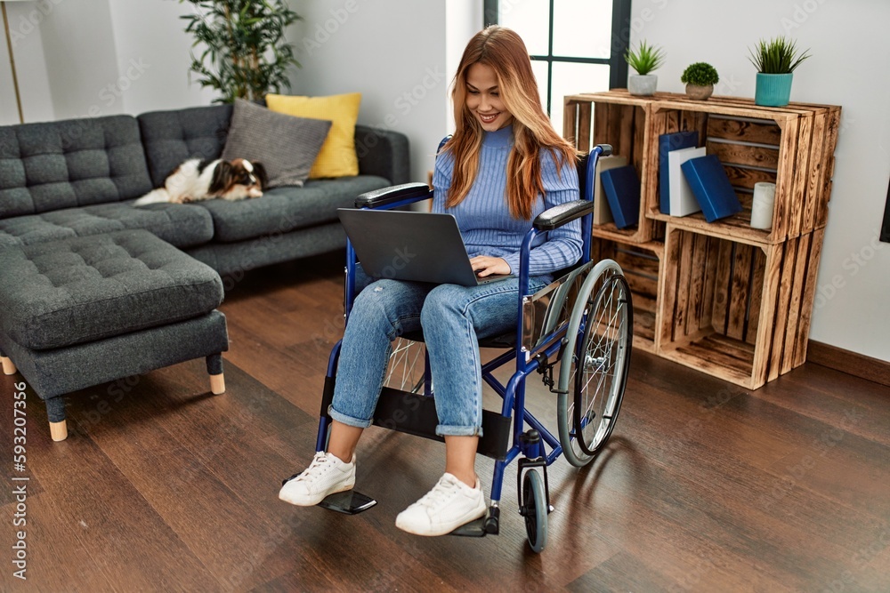 Young caucasian woman using laptop sitting on wheelchair at home Young caucasian woman using laptop sitting on wheelchair at home