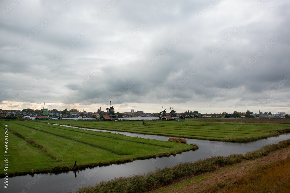 Obraz premium Beautiful landscape of a field and a river under a cloudy sky.