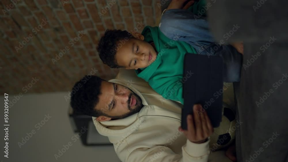 Young father with his looking something on digital tablet. Vertical view. Young father with his looking something on digital tablet. Vertical view.