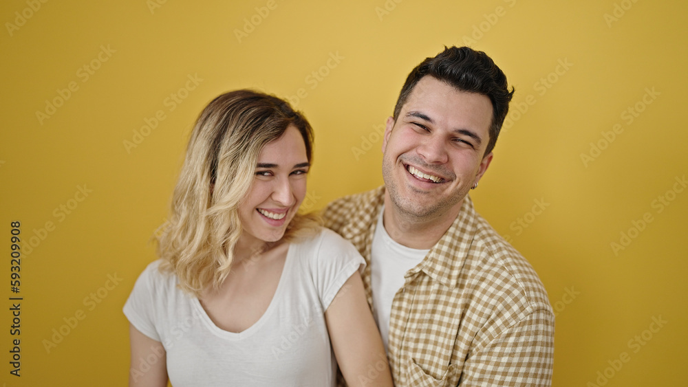Man and woman couple smiling confident standing together over isolated yellow background Man and woman couple smiling confident standing together over isolated yellow background