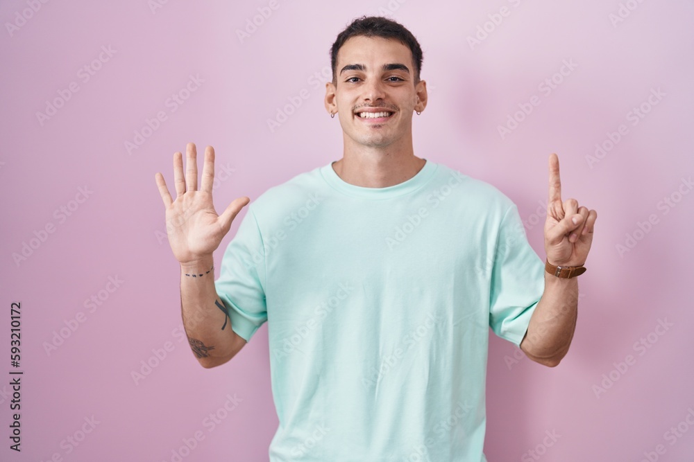 Handsome hispanic man standing over pink background showing and pointing up with fingers number six while smiling confident and happy. Handsome hispanic man standing over pink background showing and pointing up with fingers number six while smiling confident and happy.