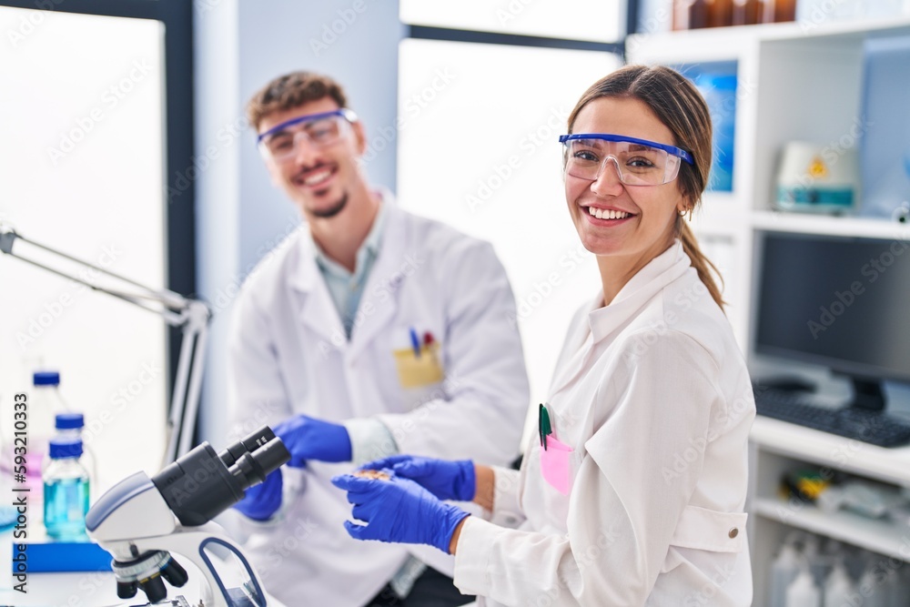 Young man and woman scientists workers using microscope at laboratory Young man and woman scientists workers using microscope at laboratory