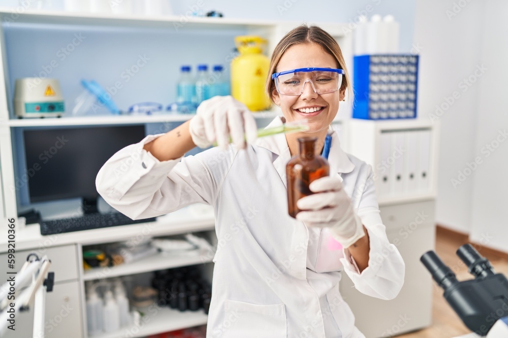 Young hispanic woman scientist pouring liquid on bottle at laboratory Young hispanic woman scientist pouring liquid on bottle at laboratory