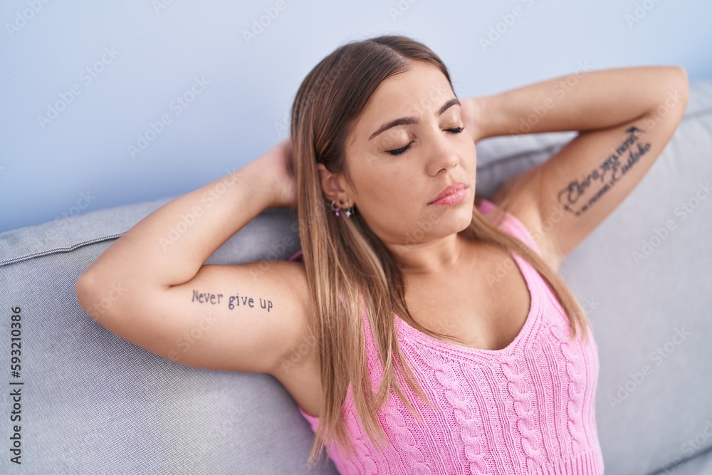 Young beautiful hispanic woman relaxed with hands on head sitting on sofa at home Young beautiful hispanic woman relaxed with hands on head sitting on sofa at home