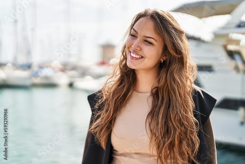 Young beautiful hispanic woman smiling confident looking to the side at seaside