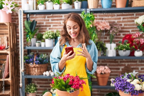 Young beautiful hispanic woman florist smiling confident using smartphone at florist