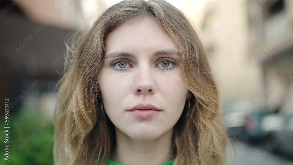 Fototapeta premium Young blonde woman standing with serious expression at street